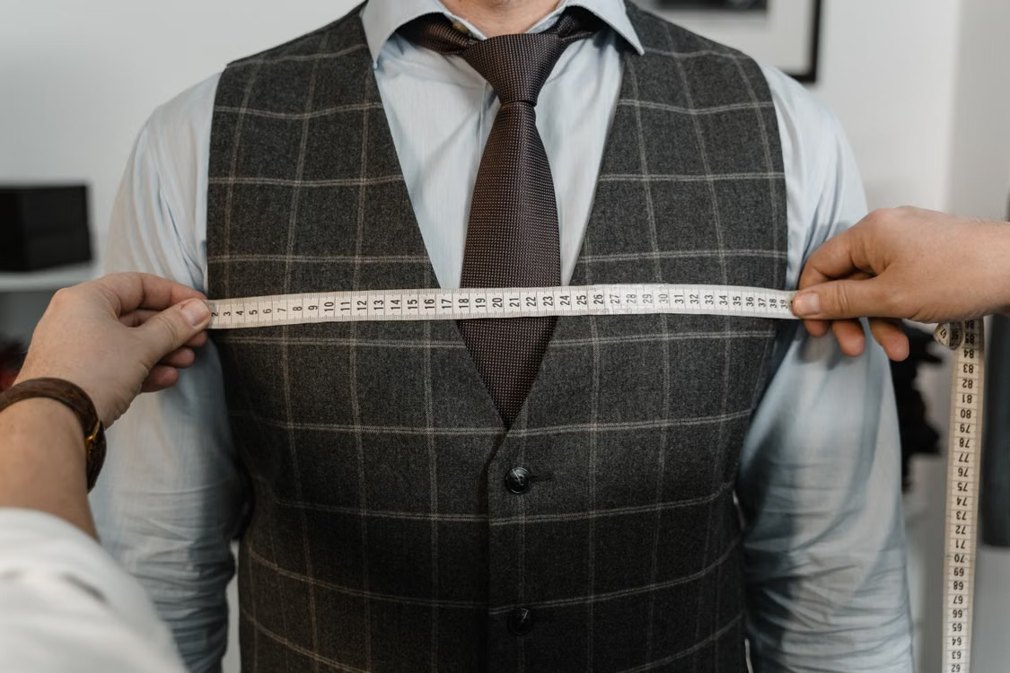 Buyer measuring an unbranded vest sample with a tape measure during apparel sample approval