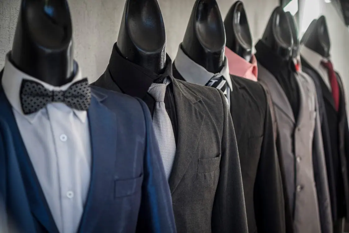 Row of tailored jackets and shirts displayed on headless mannequins in a clothing showroom