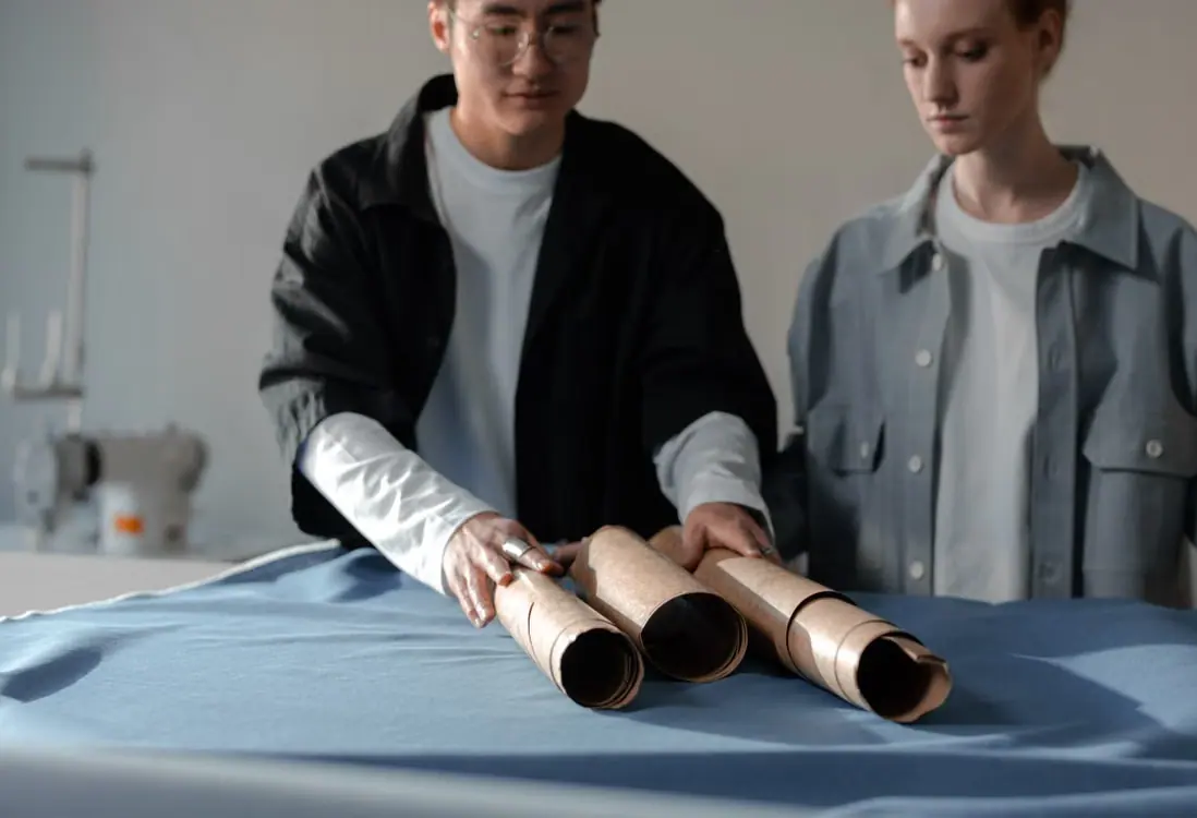 Apparel development team reviewing fabric rolls and garment materials on a cutting table