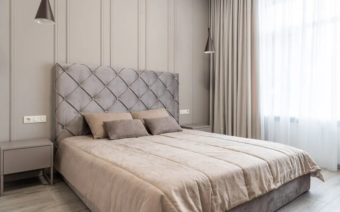 Neutral upholstered bed dressed with coordinated beige bedding in a bright bedroom