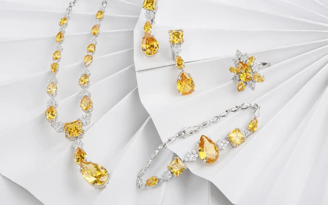 Gold-tone crystal jewellery arranged on white fabric for apparel accessory planning