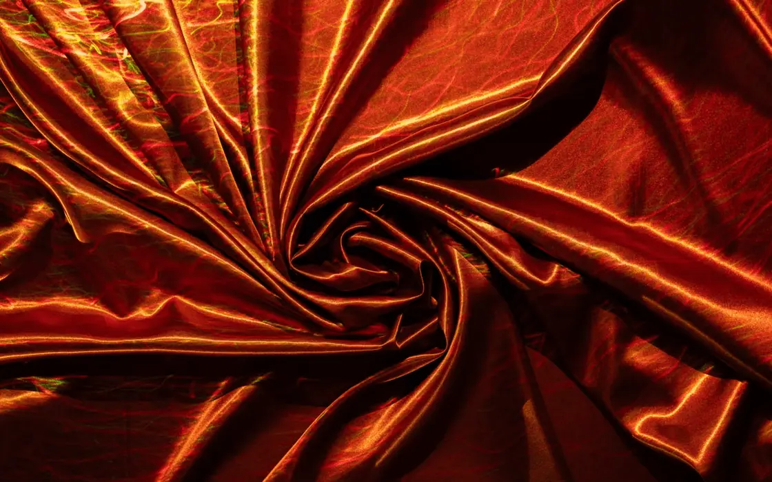 Red silk fabric draped in folds for textile material review